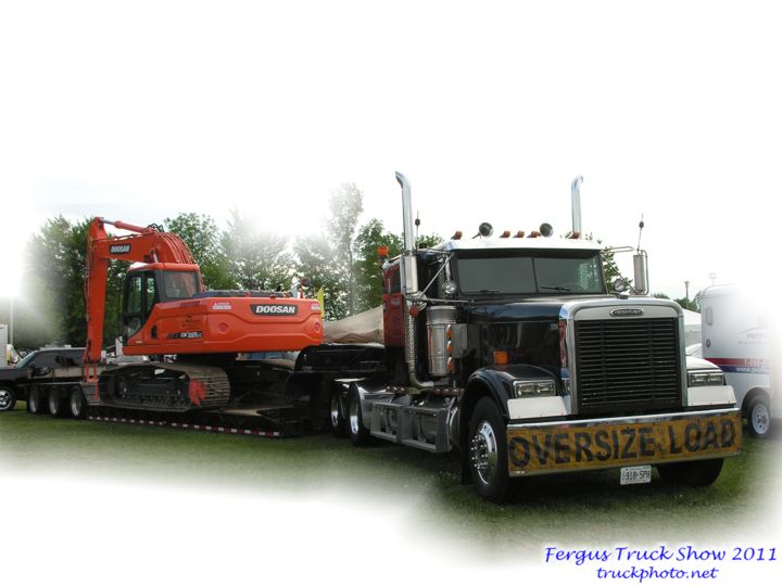Freightliner with low boy trailer hauling Doosan excavator