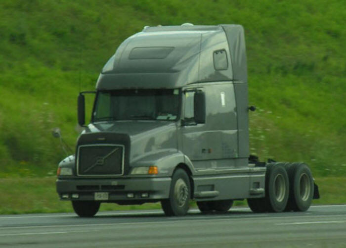 Volvo Truck bobtail grey green driving on road on a grey cloudy day