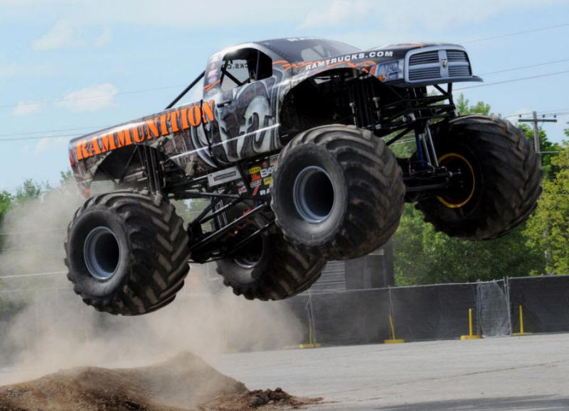 Rammunition Monster Truck flying into the air off a dirt ramp in the dust