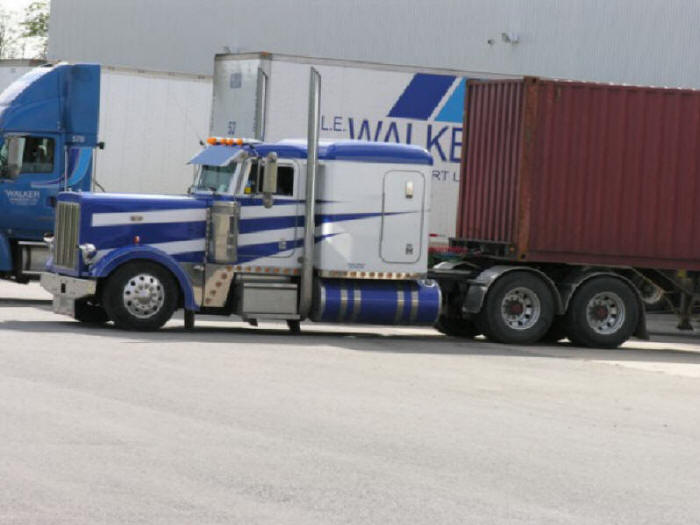 Peterbilt white and blue container trailer hauler at loading dock